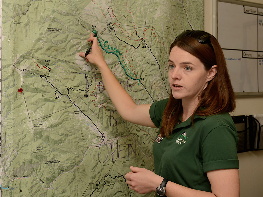 A student pointing to a trail on a large map hung on the wall